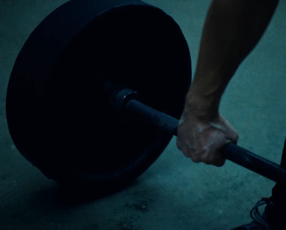 A chalked hand gripping the knurling of a loaded barbell